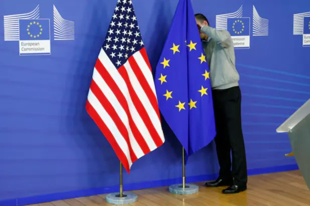 A worker adjusts European Union and US flags at the EU Commission headquarters in Brussels, November 11, 2013. 