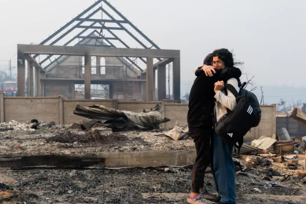 Mirtza Aguilera, right, and her daughter embrace in front of their home burned by wildfires in Tome, Chile, Monday, Jan. 19, 2026. (AP Photo/Javier Torres)