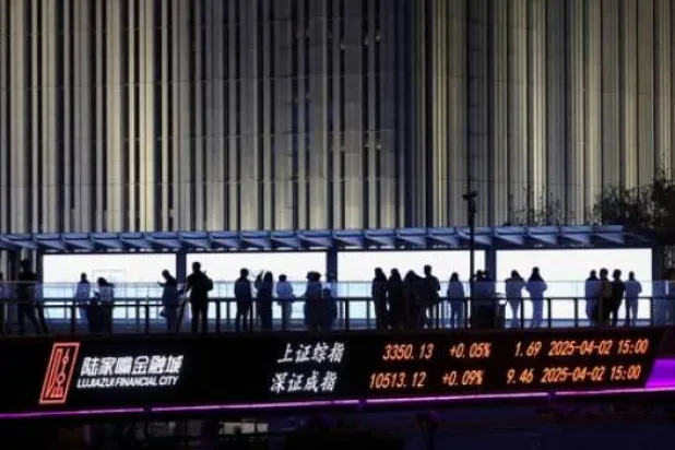 لوحة إلكترونية تعرض مؤشرات بورصتي شنغهاي وشنتشن بينما يمشي أشخاص على جسر للمشاة في منطقة لوجيازو المالية في شنغهاي (رويترز)