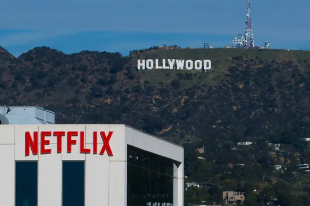 A Netflix sign is displayed atop a building in Los Angeles, on Dec. 18, 2025, with the Hollywood sign in the distance. (AP) 
