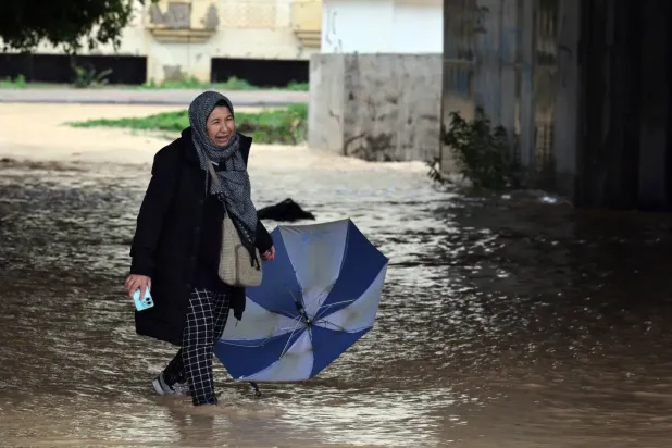Yağmur sularında yürümeye çalışan bir kadın (EPA)
