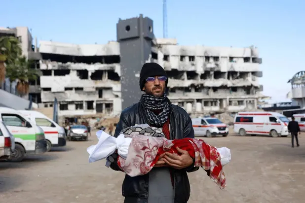 A Palestinian man carries the body of his three-month-old daughter on Tuesday after she died from the cold in Gaza City. (AFP)