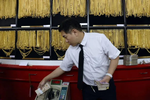 صائغ ذهب يعدّ الأوراق النقدية خلال عملية تداول الذهب في متجر للذهب في بانكوك  (إ.ب.أ)