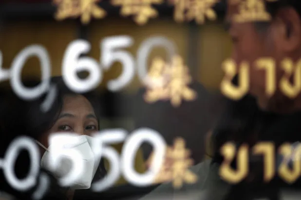 A customer waits his turn to trade gold behind a glass window displaying gold prices at a gold shop in Bangkok (EPA)