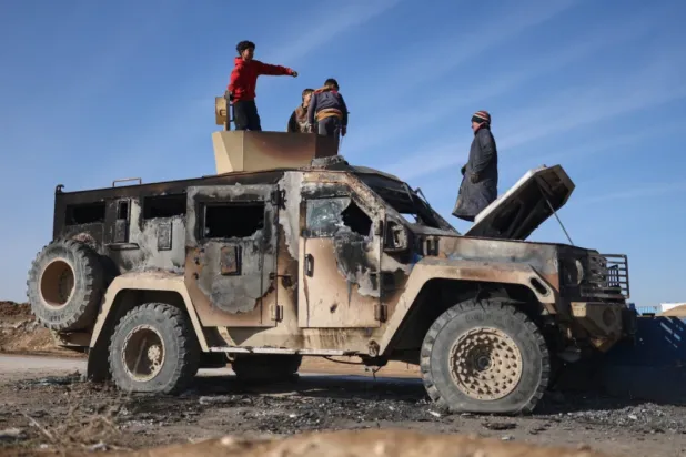 Local youth play atop of a damaged armored vehicle belonging to the Syrian Democratic Forces (SDF) at the site of clashes with Syrian government forces in the village of al-Hol in northeastern Syria’s Hasakeh province, Syria, Wednesday, Jan. 21, 2026. (AP Photo/Ghaith Alsayed)

