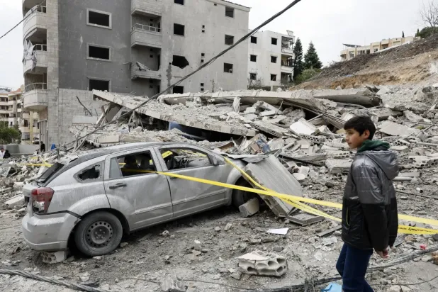 Lübnan'ın güneyindeki Kanarit kasabasına çarşamba günü İsrail'in düzenlediği hava saldırısında yıkılan bir binanın önündeki çocuk (EPA)
