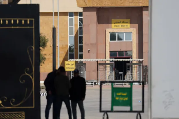 People stand at the gate of the border crossing between Egypt and the Gaza Strip, in Rafah, Egypt, February 11, 2025. REUTERS/Amr Abdallah Dalsh