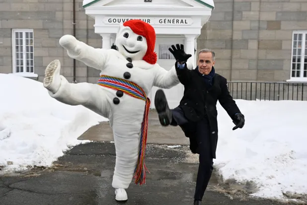 رئيس الوزراء الكندي مارك كارني يرفع ساقه في رمزية كرنفالية تقليدية في مدينة كيبيك (أ.ب)