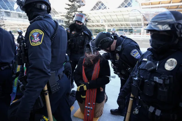 ضباط شرطة أميركيون يعتقلون رجلاً خلال مسيرة احتجاجية ضد قوانين الهجرة في مدينة مينيابوليس بولاية مينيسوتا (رويترز)