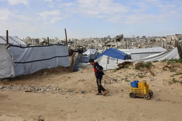 A Palestinian child pulls containers filled with water at the Jabalia refugee camp in the northern Gaza Strip (AFP)