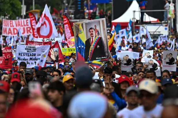 Devrik Venezuela Devlet Başkanı Nicolas Maduro'nun destekçileri, Maduro'nun fotoğraflarını ve serbest bırakılmasını talep eden pankartlar taşıdı (AFP)