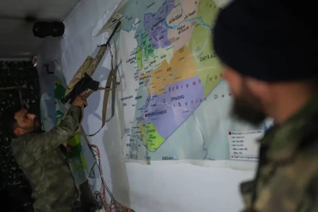 Dün Rakka kırsalındaki Ayn İsa'dan çekildikten sonra SDG tarafından boşaltılan bir tünelde Suriye haritasının önünde duran Suriye hükümeti güçlerinin iki üyesi (AP)