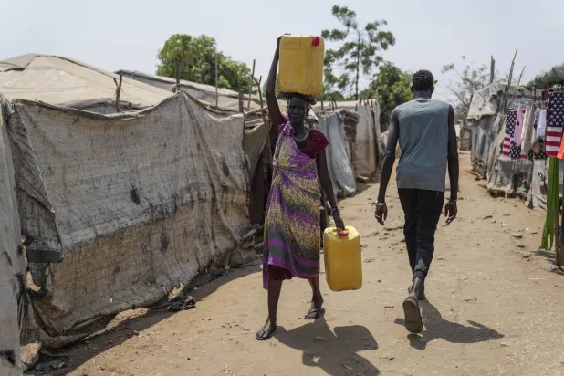 نازحة تحمل الماء على رأسها في مخيم جوبا للنازحين جنوب السودان (أ.ب)
