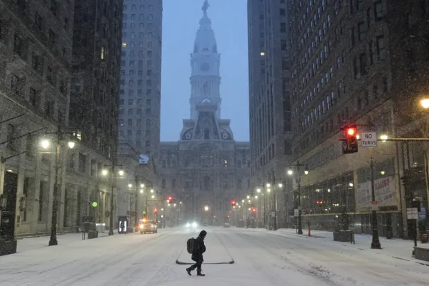 A person walks across a street during a winter storm in Philadelphia, Sunday, Jan. 25, 2026. (AP Photo/Matt Rourke)