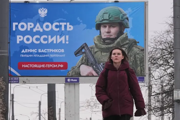 امرأة تمر أمام لوحة إعلانية تعرض جندياً روسياً مشاركاً في العمليات العسكرية في أوكرانيا مع عبارة مشفرة تقول «فخر روسيا» في سانت بطرسبرغ (أ.ب)