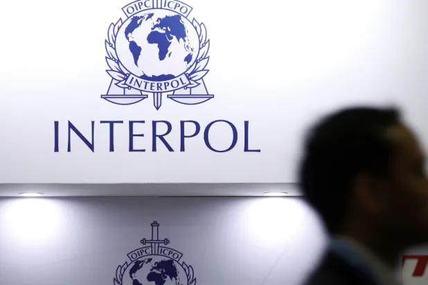 رجل يمر أمام شعار «الإنتربول» (رويترز)