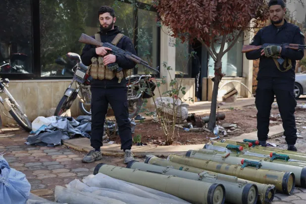 عنصرين من قوى الأمن السورية يقفان بجوار شحنة أسلحة كانت معدة للتهريب إلى لبنان (سانا)  