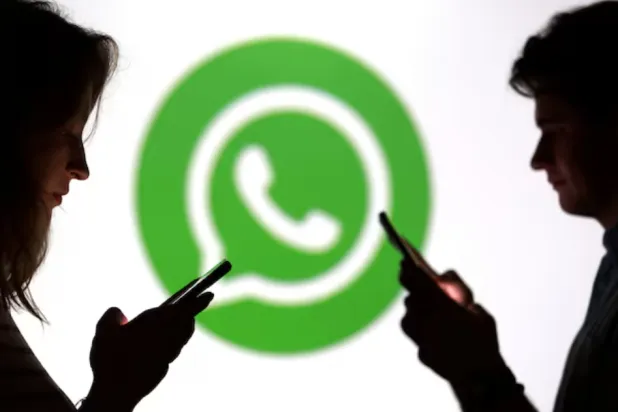Teenagers pose for a photo while holding smartphones in front of a Whatsapp logo in this illustration taken September 11, 2025. REUTERS/Dado Ruvic/Illustration