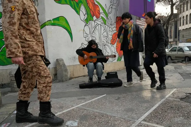 موسيقي يعزف على الغيتار في شارع وسط مدينة طهران (أ.ب)