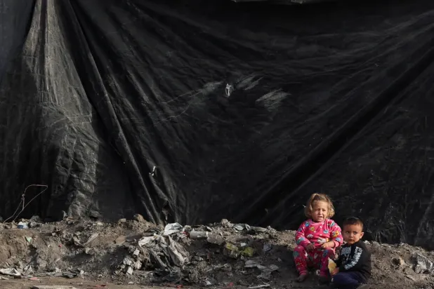 Gazze şehrindeki bir kampta çadırların yanında duran yerinden edilmiş Filistinli çocuklar (Reuters)