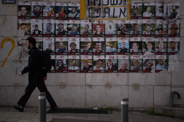 رجل يمر أمام صور لرهائن اختطفتهم حركة «حماس» معروضة في أحد شوارع القدس (أ.ب)