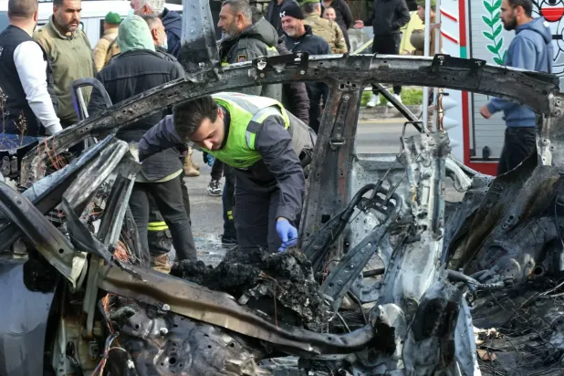 Lübnan'ın güneyindeki ez-Zehrani bölgesinde İsrail hava saldırısının hedef aldığı bir arabanın enkazını inceleyen sivil savunma gönüllüsü (AFP)