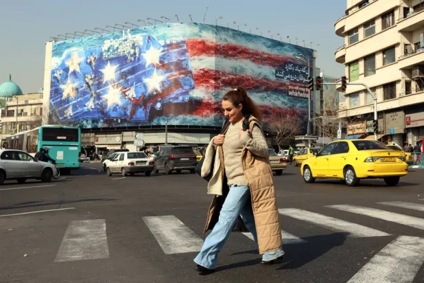 İranlı bir kadın, Tahran'ın merkezindeki Enghelab (Devrim) Meydanı'nda, devasa bir Amerikan karşıtı pankartın yakınından geçiyor (EPA)