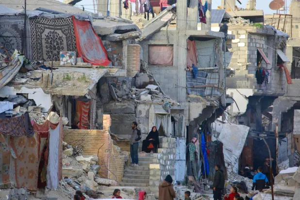 فلسطينيون يجلسون وسط المنازل المدمرة في خان يونس (أ.ف.ب)