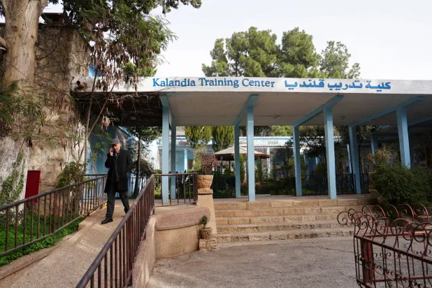 بهاء عوض مدير مركز تدريب «الأونروا» في قلنديا يتحدث عبر الهاتف أمام المركز بعد أن أفاد الموظفون بأن إسرائيل قطعت التيار الكهربائي عن المنشأة بالقرب من رام الله في الضفة (رويترز)