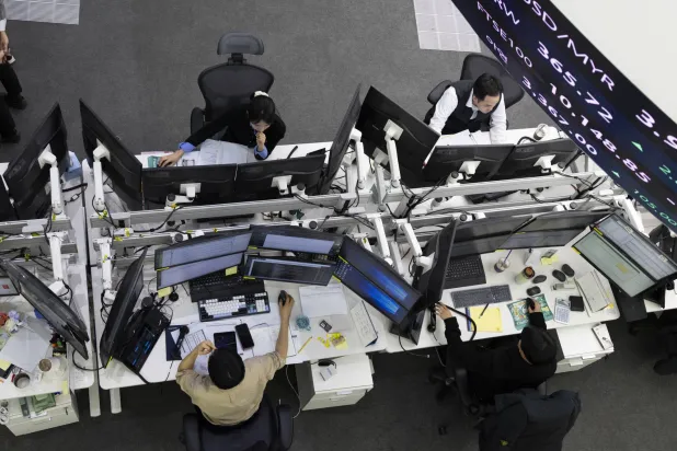 متعاملون كوريون جنوبيون يعملون أمام شاشات التداول في بنك هانا في سيول (إ.ب.أ)