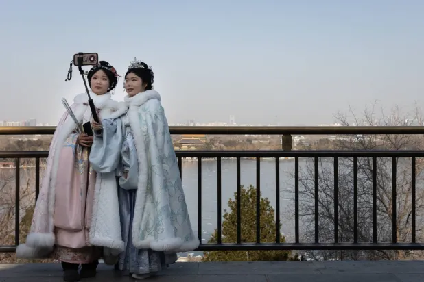 مواطنون يرتدون زياً تقليدياً ويلتقطون صوراً تذكارية في إحدى الحدائق بالعاصمة الصينية بكين (إ.ب.أ)