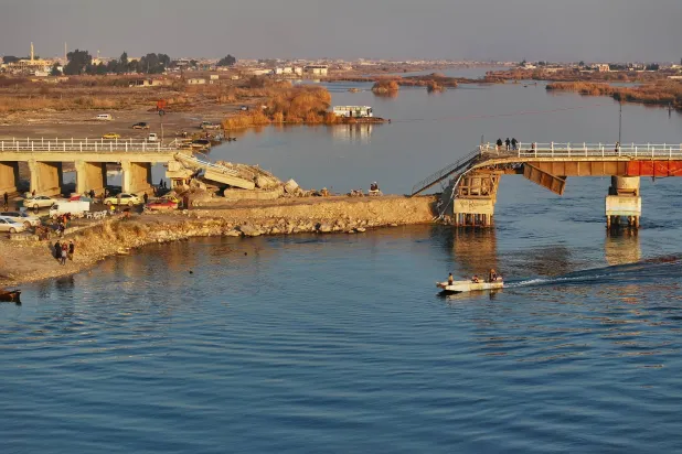 يعبر سكان الرقة بشمال سوريا جسراً متضرراً فوق نهر الفرات الأحد الماضي (إ.ب)