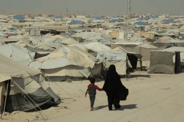 امرأة وطفل يسيران في «مخيم الهول» بسوريا (رويترز - أرشيفية)