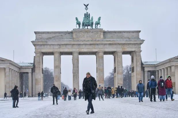 People walk past the Brandenburg Gate as winter weather covers the city, in Berlin, Germany, Friday, Jan. 30, 2026. (AP Photo/Ebrahim Noroozi)