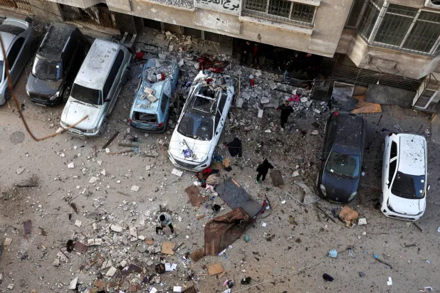 فلسطينيون يتفقدون موقع الغارة الإسرائيلية على مدينة غزة اليوم (رويترز)