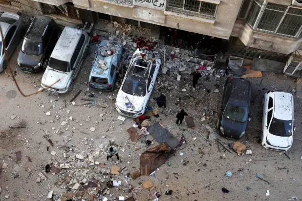 Filistinliler, bugün İsrail’in Gazze kentine düzenlediği saldırının ardından hedef alınan noktayı inceliyor. (Reuters)