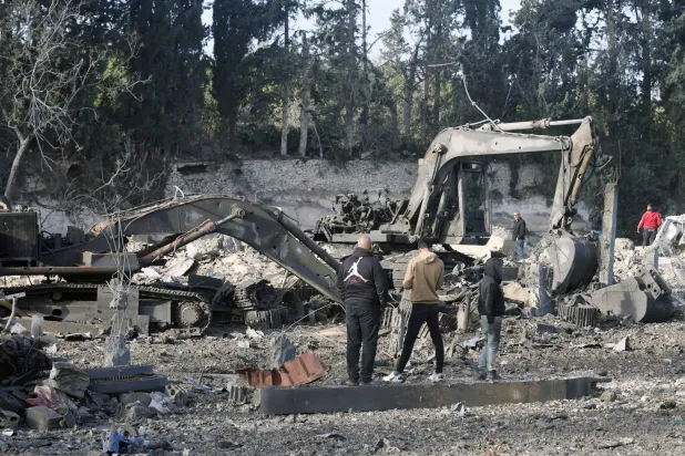 سكان يعاينون آليات لإعادة الإعمار متضررة جراء غارات إسرائيلية استهدفت معرضاً لها في منطقة الداوودية بجنوب لبنان (إ.ب.أ)