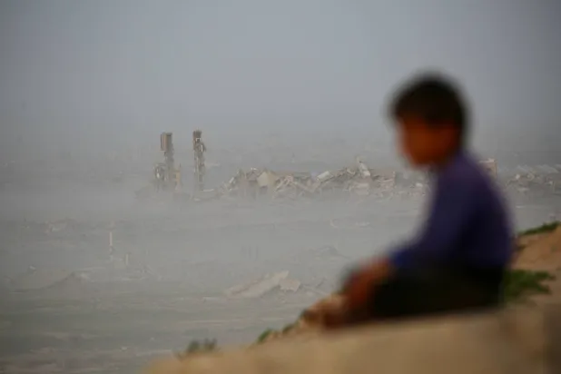 A young boy sits overlooking destroyed buildings at Nuseirat camp for Palestinian refugees in the central Gaza Strip on January 31, 2026. (AFP)