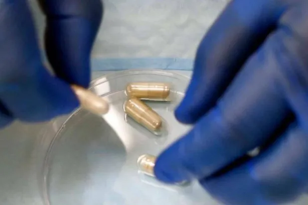 طبيب أمراض معدية يعد كبسولات دواء تحتوي على عينات براز في مختبر بكندا (أرشيفية - أ.ب)