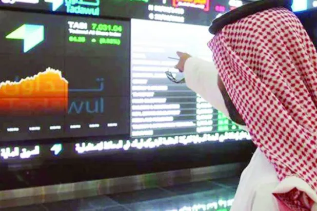 متداول يشير إلى تحرك الأسهم على شاشة في «السوق المالية السعودية» (رويترز)