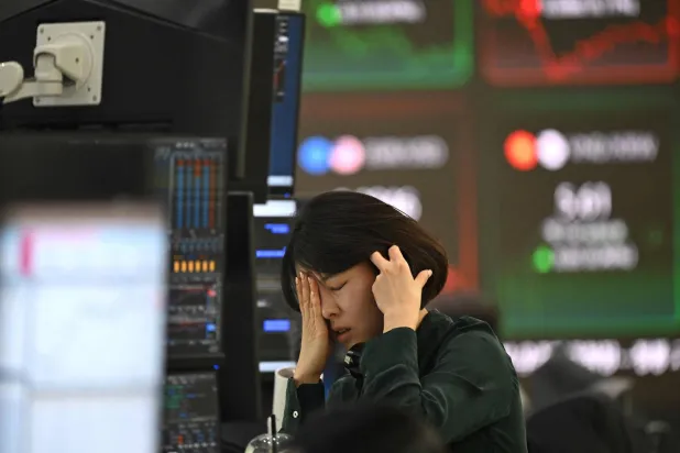 متداولة تتفاعل في سوق العملات أثناء متابعتها لأسعار الصرف بالمقر الرئيسي لبنك هانا في سيول (أ.ف.ب)