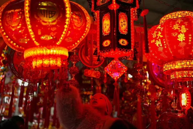 A toddler held by a woman looks at the prosperity decorations at a booth for the upcoming Chinese Lunar New Year, at a New Year Bazaar, in Beijing, China, Sunday, Feb. 1, 2026. (AP)