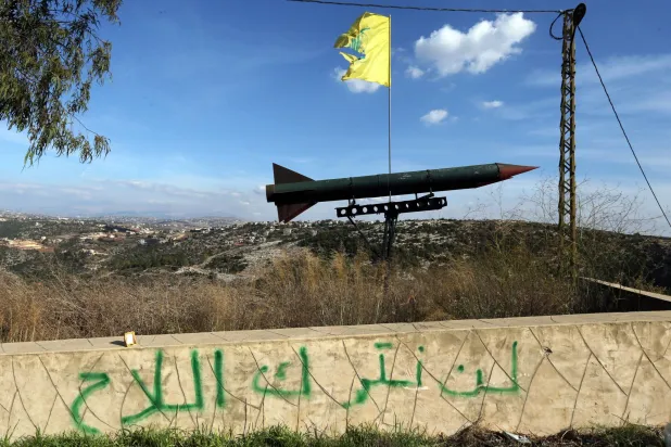 مجسّم لصاروخ رفعه «حزب الله» بمنطقة قلاويه في جنوب لبنان فوق شعار «لن نترك السلاح» (أرشيفية - إ.ب.أ)