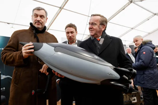 وزير الدفاع الألماني بوريس بيستوريوس (يمين) يفحص غواصة مسيرة خلال زيارته مركزاً للابتكار تابعاً للجيش الألماني في منطقة إردينغ بالقرب من مدينة ميونيخ جنوبي ألمانيا (أ.ف.ب)