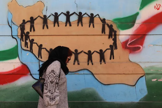  A woman walks past the flag and map of Iran painted on a wall in the Iranian capital Tehran on January 31, 2026, ahead of the 47th anniversary of the 1979 revolution. (AFP) 