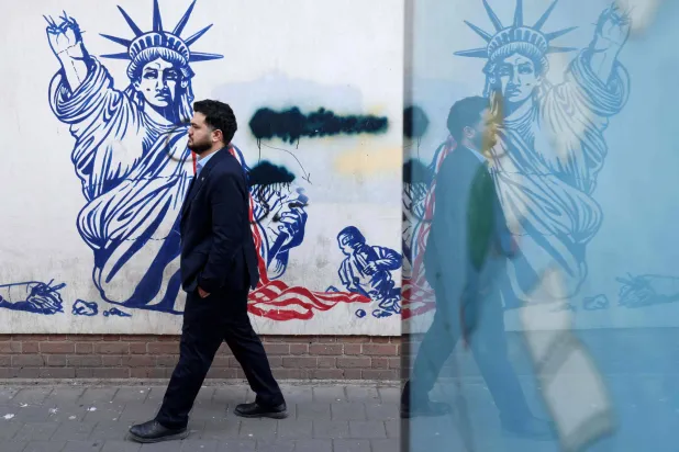 A man walk past a mural depicting the Statue of Liberty with the torch-bearing arm broken, painted on the outer walls of the former US embassy in Tehran, colloquially-referred to as the "Spy Den,"on February 1, 2026. (AFP)