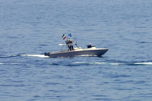 An Iranian Revolutionary Guard vessel watches an American warship in the Strait of Hormuz, May 19, 2023. (AP) 