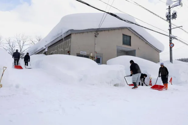  People clear snow near a building in Aomori, northern Japan, Monday, Feb. 2, 2026. (Kyodo News via AP)