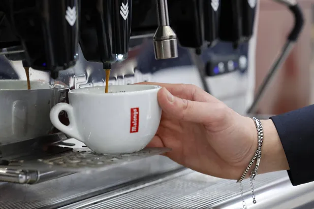 سيدة تحضر كوباً من القهوة في مدينة نيس الفرنسية (إ.ب.أ)