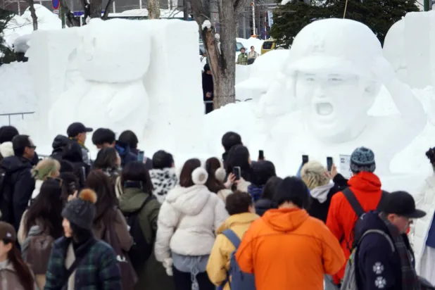 مواطنون وسواح يشاهدون منحوتات في معرض الجليد السنوي شمال اليابان (إ.ب.أ)